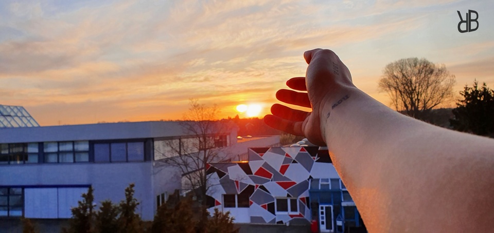 Die Hand streckt sich zum Sonnenaufgang